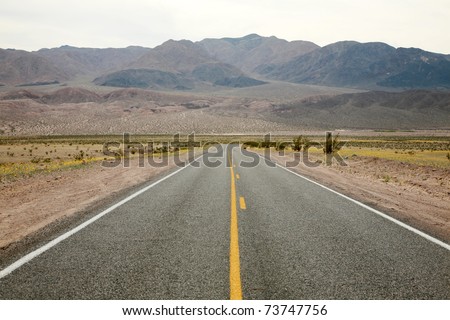a two lane highway stretches for miles and miles in the hot summer sun of Death Valley California