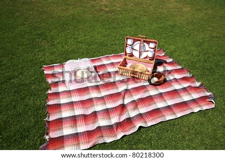 a picnic lunch outdoors in a nice field or park on sunny spring or summer day. picnic includes sandwich, chips, pie, drinks, a blanket and a baseball and glove with a blue sky and green grass.