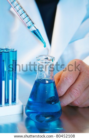 a medical research scientist or chemist works in a laboratory. light in a blue light. blue being a popular color for health, science, calm, relaxation, and just generally a great cool color