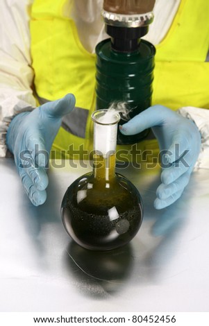 illegal drug mfg, chemical - a man in a hazmat suit, gas mask, and gloves and vest examines a dangerous chemical or drug he has manufactured in his laboratory. isolated on white room for your text