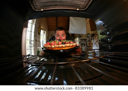 a young man is excited about the fruit tart he just baked in his oven