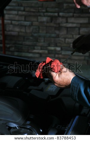 Detail of a car mechanic working on a car at the car repair shop, car in background