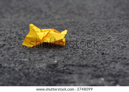 A crumpled lined writing paper on road pavement. Shallow DOF.