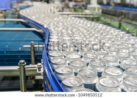 Conveyor line carrying thousands aluminum beverage cans at factory. Concept of industrial growth.
