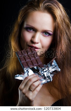 sexy young woman eating chocolate on a black background