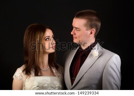 the bride and groom on a black background in the studio looking at each other
