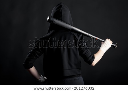 Young woman with a baseball bat. View from the back. street hoodlum