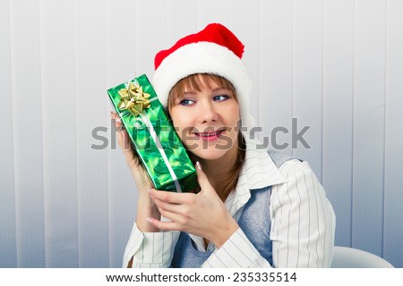 Attractive girl in the office in Santa hats with a gift