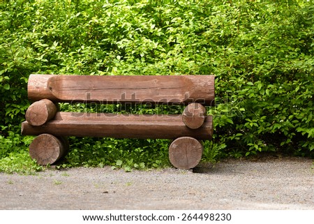 Massive wooden bench in the park on a background of vegetation