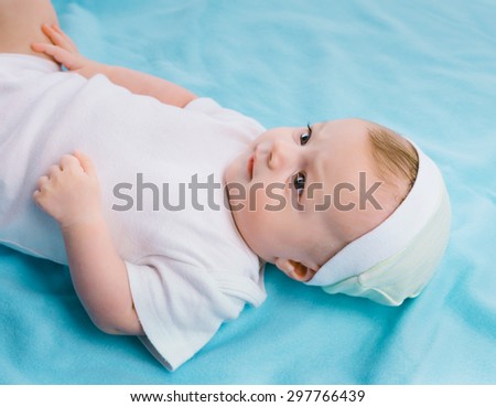 baby in cap lying on a blue blanket