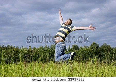 The young man joyfully jumps up in a grass