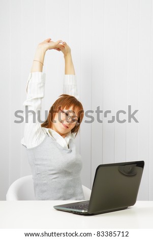 tired girl with a laptop stretches in the workplace