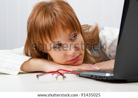 Tired girl lies on a table with a laptop