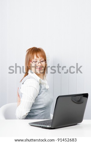 tired girl with a laptop stretches in the workplace