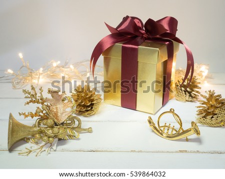 Gold box with red ribbon and decoration golden object white background  on wooden table for Christmas and The New Year .