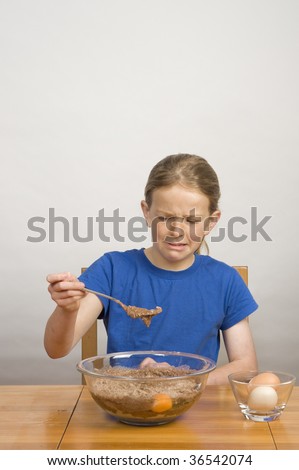 young girl making funny face while mixing cake batter