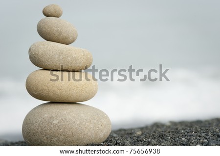 pile of balanced rocks on black sand beach with ocean in background