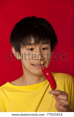 stock photo teenage Asian Chinese boy making funny face at burning hot red