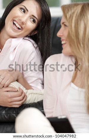 Two woman in their sitting room chatting and having fun on an electronic tablet