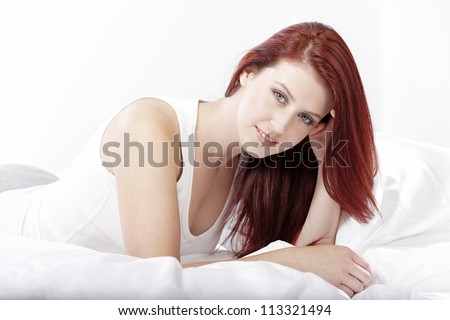 Young woman lying on her white bed at home relaxing