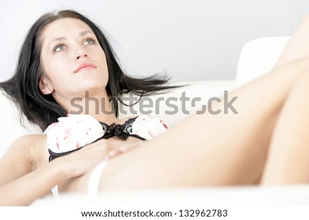 Beautiful young woman lying on a white sofa with her feet up in her underwear.