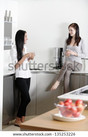 Two friends catching up over coffee in their kitchen.