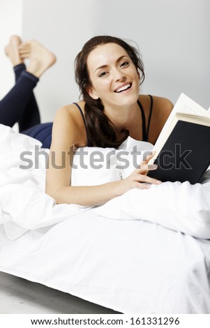 Young woman reading her book in bed