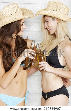 Two friends having fun in bikinis and summer hats