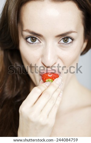 Attractive young woman biting into a fresh strawberry