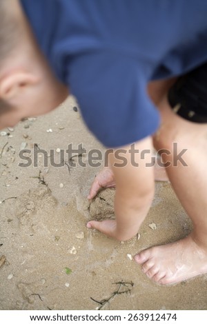 Young boy searching for treasure in the sand and mud