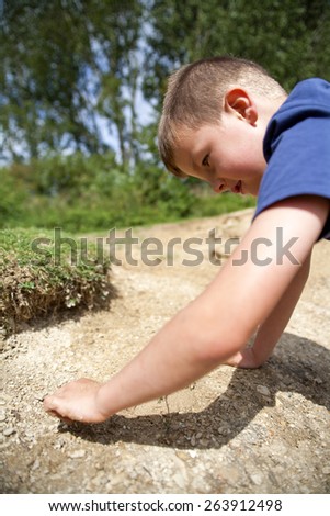 Young boy searching for treasure in the sand and mud