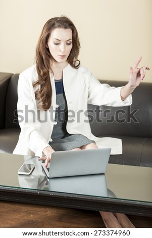Business woman using her laptop and holding her hand up to call someone