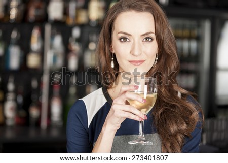 Attractive young woman standing in a wine bar with a glass of wine