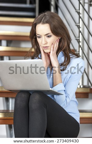 Young woman using a laptop computer looking concerned and worried