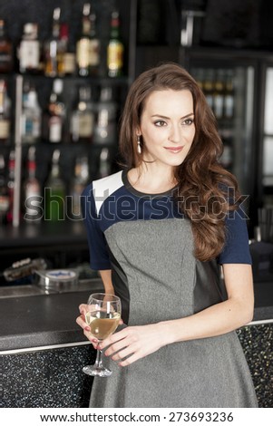 Attractive young woman standing in a wine bar with a glass of wine
