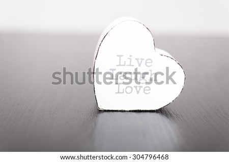 Single white wooden heart with the slogan live laugh love on the front