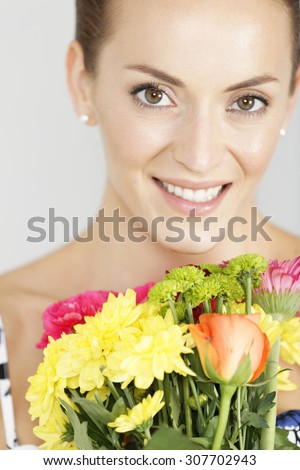 Beautiful young woman in a summer dress holding a fresh bouquet of flowers smiling
