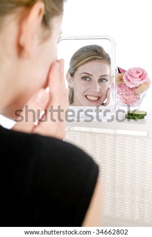 Female model looking into mirror applying cream