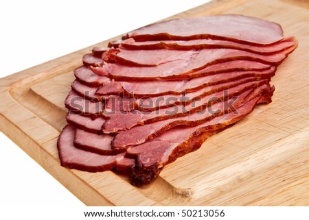 Smoked ham slices on wooden board isolated over white background.