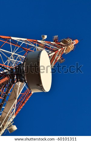 Telecommunication mast with microwave link and TV transmitter antennas over a blue sky.