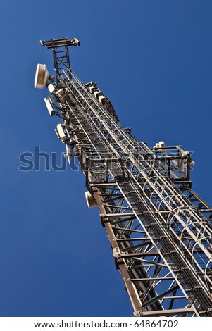 Telecommunication mast with microwave link antennas over a blue sky.
