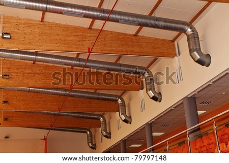 Ventilation and air-conditioning metal ducts under roof wooden construction.