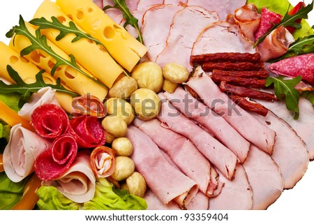 Dish with sliced smoked ham, salami rolls and cheese over white background.