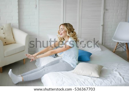 Young attractive woman, cheerful blonde in bed at home, starting a new day with a charge and cheerful mood
