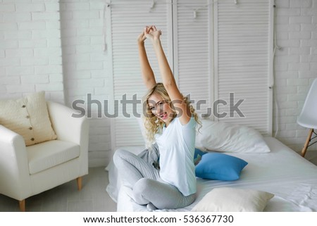 Young attractive woman, cheerful blonde in bed at home, starting a new day with a charge and cheerful mood