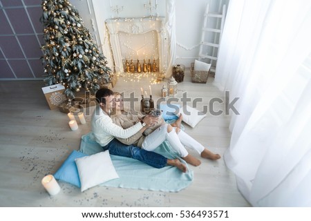 Young beautiful family with a cat, in a cozy room with a Christmas tree, relax, enjoy the holidays