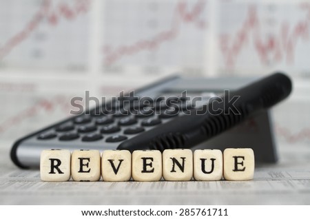 Revenue word built with letter cubes on newspaper background