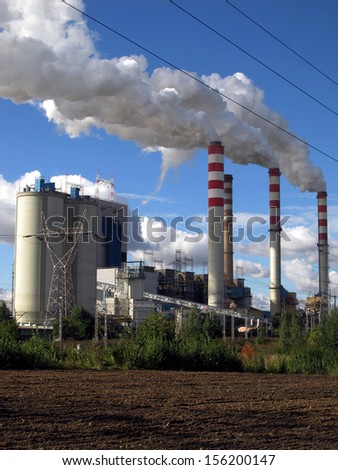 brown-coal power plant with chimney giving off large amounts of gas to the blue sky
