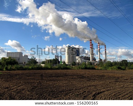 brown-coal power plant with chimney giving off large amounts of gas to the blue sky
