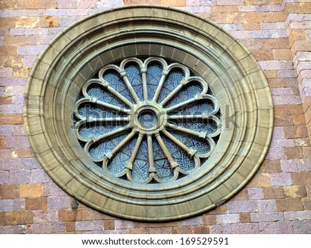 rosette or circular window filled with stained glass and ornamentation in the facade of one of the churches in Bolzano, Italy